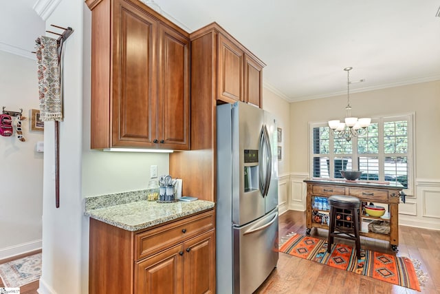 kitchen featuring hardwood / wood-style flooring, stainless steel fridge, brown cabinets, and crown molding