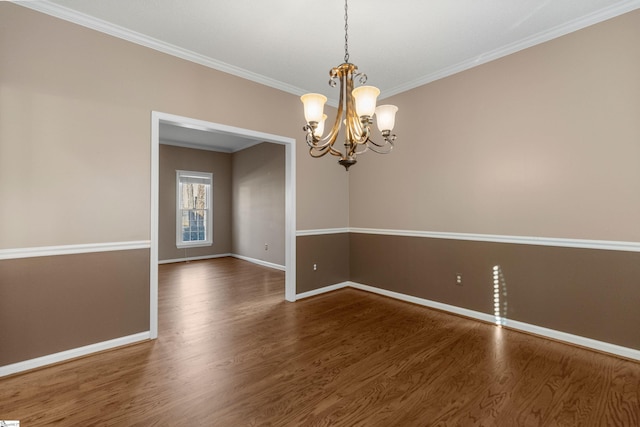 unfurnished room featuring an inviting chandelier, crown molding, baseboards, and wood finished floors