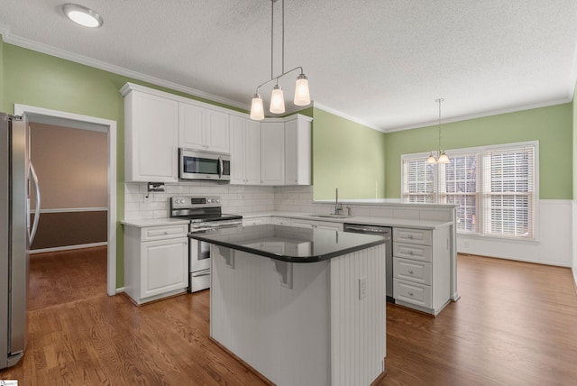 kitchen with stainless steel appliances, dark wood-type flooring, a peninsula, and white cabinetry