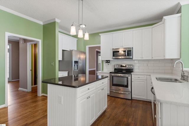 kitchen with stainless steel appliances, a sink, white cabinets, backsplash, and dark wood finished floors