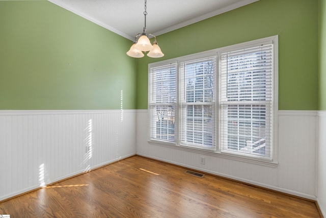 spare room with wainscoting, visible vents, plenty of natural light, and wood finished floors