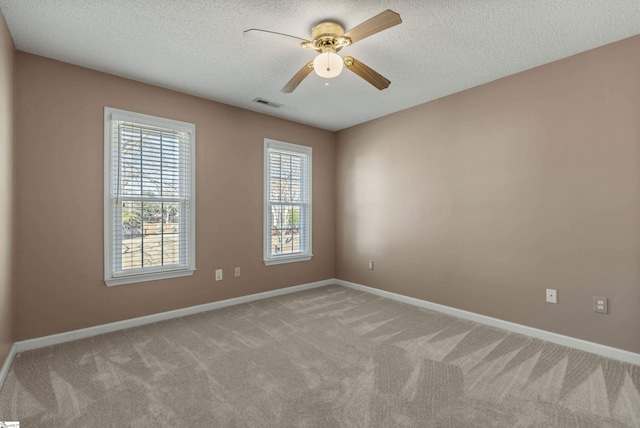 unfurnished room featuring visible vents, light carpet, a textured ceiling, and baseboards