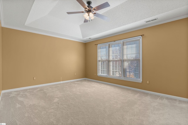 carpeted spare room with a textured ceiling, ceiling fan, visible vents, baseboards, and a tray ceiling