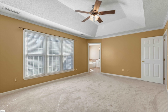 unfurnished bedroom featuring a tray ceiling, carpet, crown molding, visible vents, and a textured ceiling