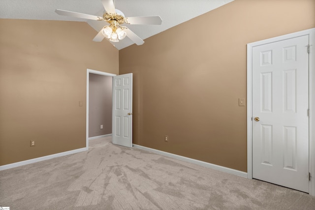 spare room featuring lofted ceiling, light colored carpet, ceiling fan, and baseboards