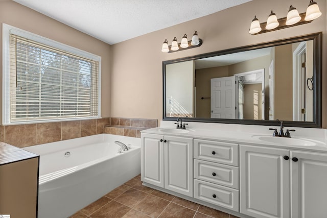 full bathroom with a textured ceiling, a sink, a bath, and tile patterned floors