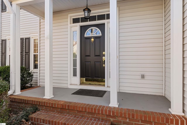 entrance to property with covered porch and brick siding