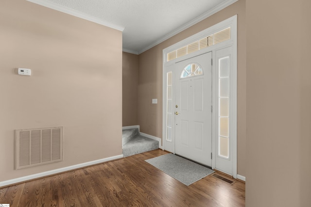 foyer with baseboards, visible vents, wood finished floors, and ornamental molding