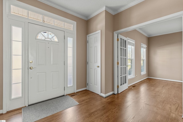 entryway featuring crown molding, visible vents, baseboards, and wood finished floors