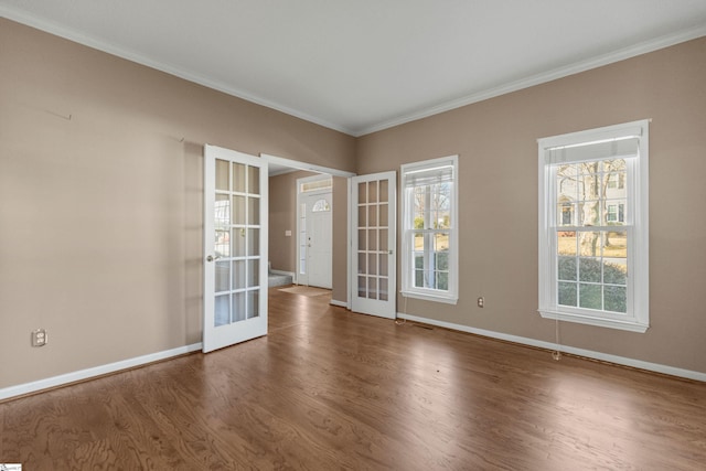 empty room with baseboards, ornamental molding, wood finished floors, and french doors