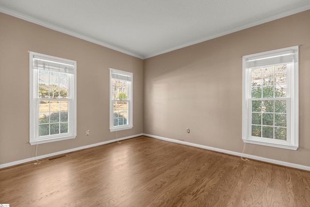 unfurnished room featuring ornamental molding, visible vents, baseboards, and wood finished floors