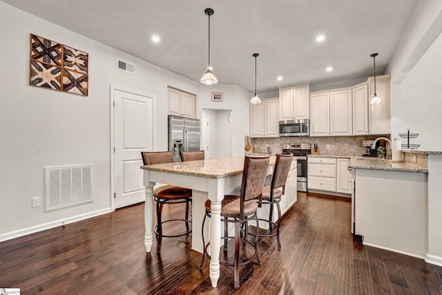 kitchen featuring a breakfast bar, visible vents, stainless steel appliances, and a center island