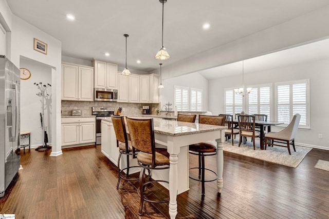 kitchen with tasteful backsplash, stainless steel appliances, dark wood finished floors, and a kitchen breakfast bar