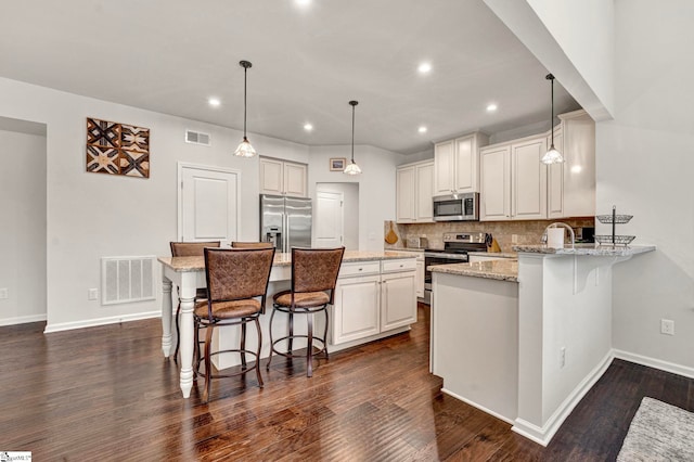 kitchen with appliances with stainless steel finishes, a breakfast bar area, and visible vents