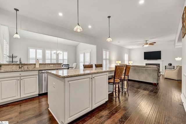 kitchen with a kitchen bar, dark wood finished floors, stainless steel dishwasher, and a kitchen island