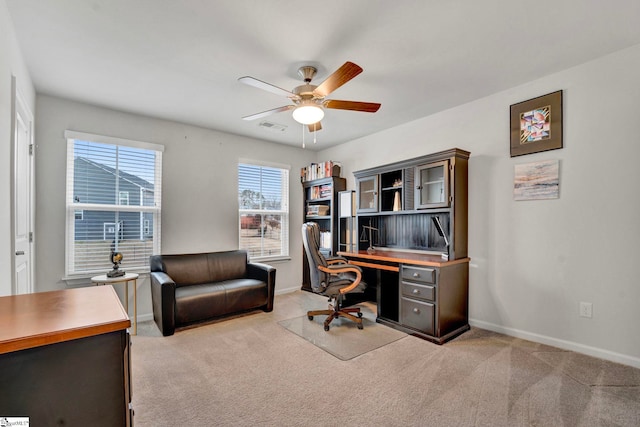 office space featuring baseboards, visible vents, ceiling fan, and light colored carpet