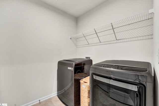 laundry area featuring laundry area, baseboards, separate washer and dryer, and tile patterned floors