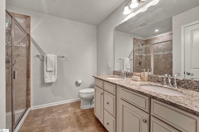 bathroom featuring double vanity, a stall shower, a sink, and baseboards