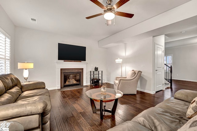 living room featuring a healthy amount of sunlight, visible vents, baseboards, and wood finished floors