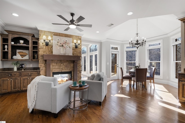 living area with a stone fireplace, plenty of natural light, dark wood finished floors, and visible vents