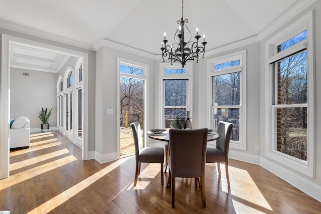 dining space with a chandelier, ornamental molding, wood-type flooring, and baseboards