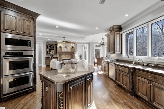 kitchen featuring stainless steel appliances, dark wood-style flooring, a fireplace, and a sink