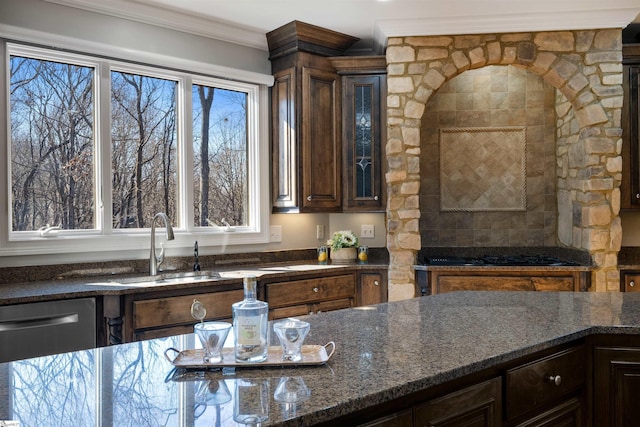kitchen with dark stone counters, dark brown cabinetry, crown molding, and a sink
