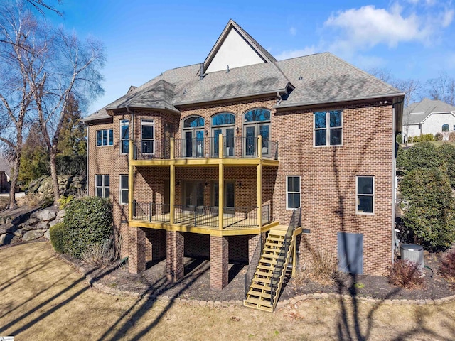back of house with a balcony, a shingled roof, stairway, and brick siding