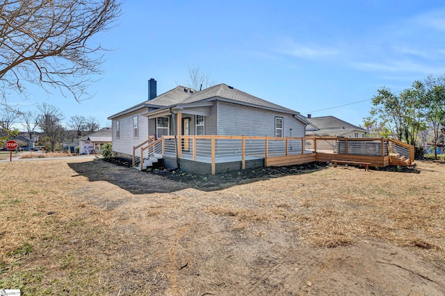 exterior space with a shingled roof, a chimney, and a deck