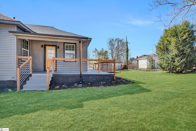 exterior space with covered porch, a lawn, and roof with shingles