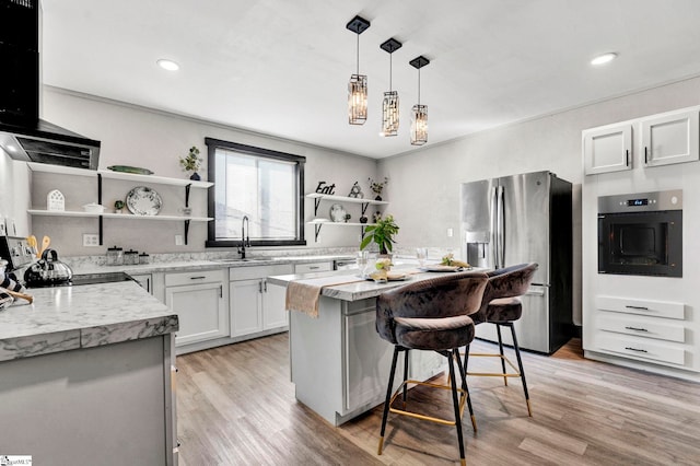 kitchen featuring stainless steel appliances, light wood-type flooring, a sink, and open shelves