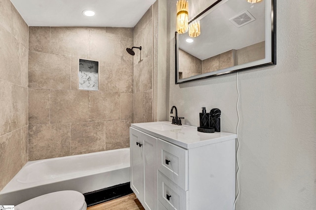 bathroom featuring shower / washtub combination, visible vents, toilet, vanity, and wood finished floors