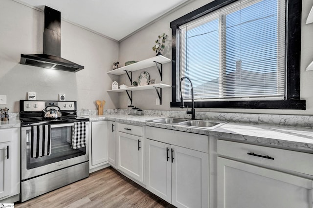 kitchen featuring light wood-style floors, white cabinetry, a sink, wall chimney range hood, and stainless steel range with electric stovetop