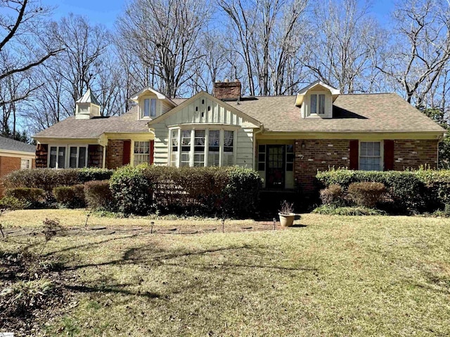 view of front facade featuring roof with shingles, a front yard, a chimney, and brick siding