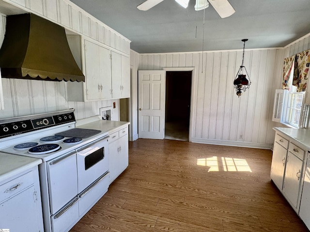 kitchen with dark wood-type flooring, light countertops, wall chimney range hood, and white electric range oven