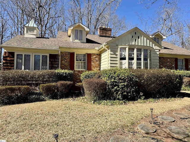 view of front of home with brick siding, a chimney, a shingled roof, and board and batten siding