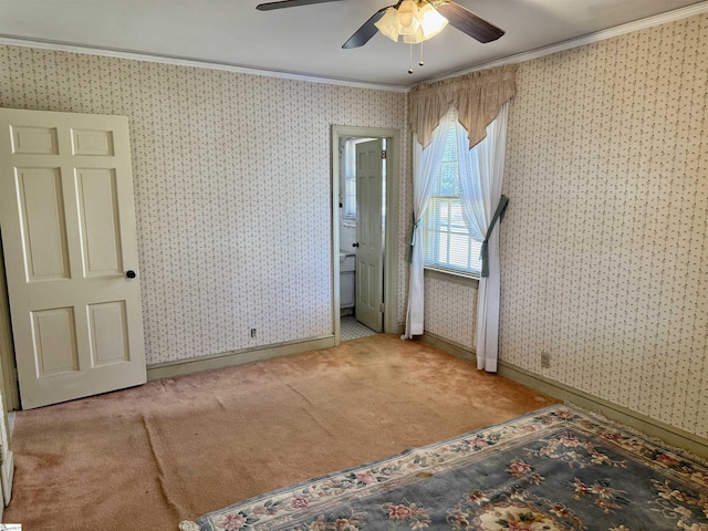 unfurnished bedroom featuring wallpapered walls, baseboards, ceiling fan, crown molding, and carpet floors