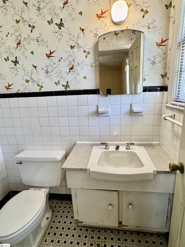 half bath with wainscoting and wallpapered walls