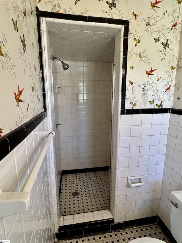 bathroom featuring wainscoting, a shower stall, and wallpapered walls