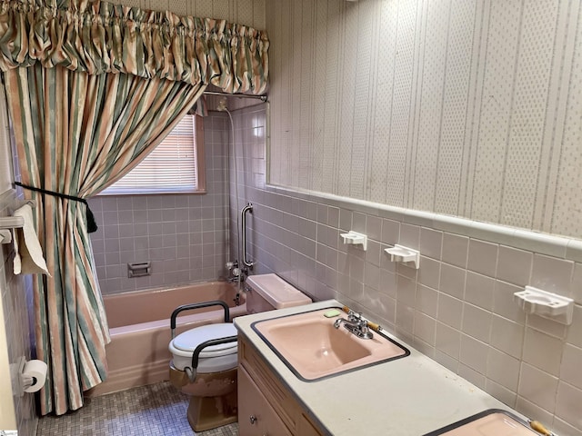 full bath with toilet, wainscoting, tile walls, and wallpapered walls