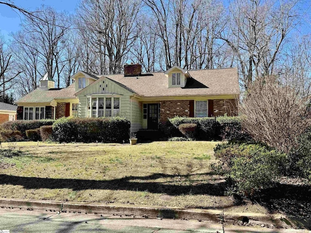 view of front of house featuring a front yard, brick siding, and a chimney