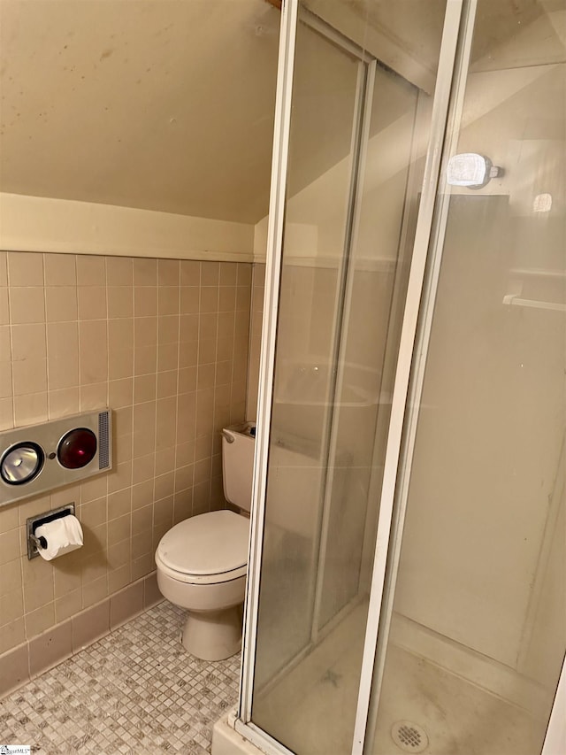 bathroom with toilet, a shower stall, tile walls, and tile patterned floors