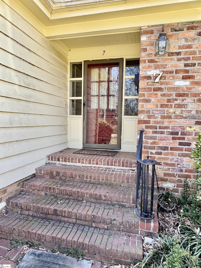 doorway to property featuring brick siding