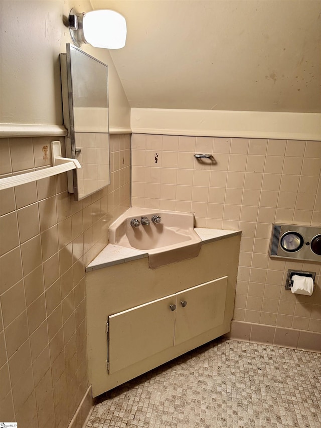 bathroom featuring lofted ceiling, tile walls, and vanity