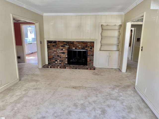 unfurnished living room featuring built in features, carpet flooring, crown molding, and a fireplace