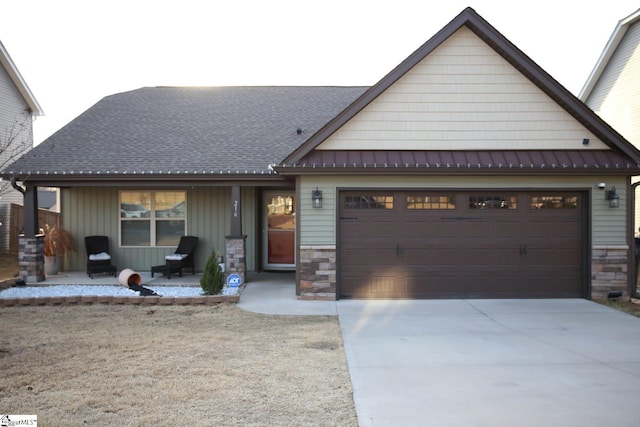 view of front of property featuring metal roof, a garage, stone siding, concrete driveway, and a standing seam roof