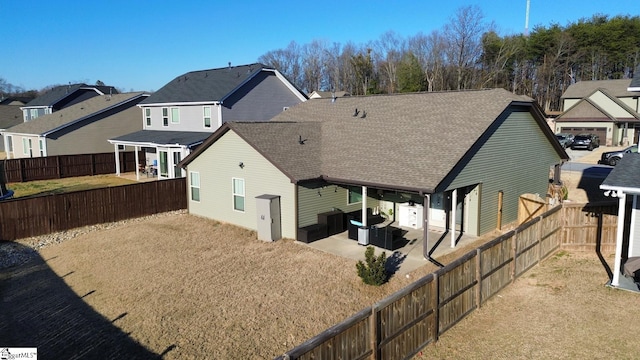 back of house with a shingled roof, a residential view, a fenced backyard, and a patio