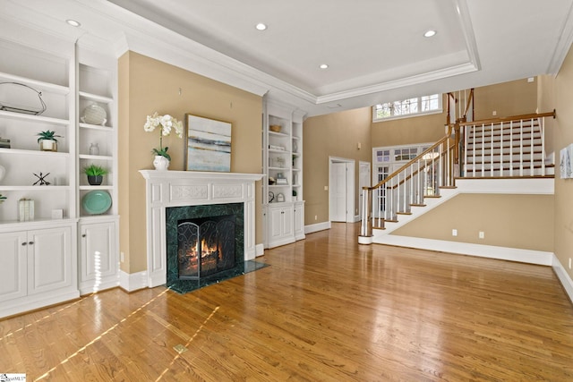 unfurnished living room with stairs, wood finished floors, a high end fireplace, and built in features