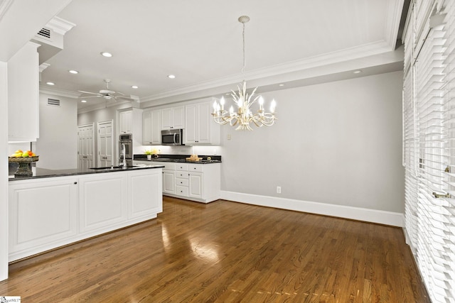 kitchen with crown molding, dark countertops, stainless steel microwave, visible vents, and dark wood-type flooring