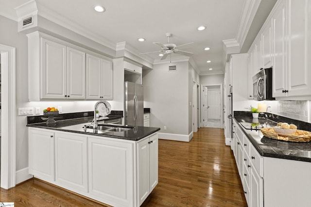 kitchen with stainless steel appliances, wood finished floors, a sink, and white cabinets